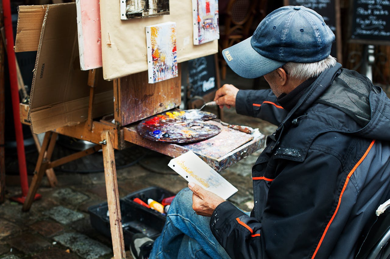 A street artist paints colorful abstracts on canvas, showcasing vibrant creativity in an outdoor setting.